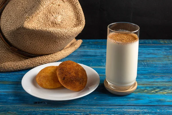 Typical colombian almojabanas, traditional colombian cheese bread over white plate with oat drink on wood table. Traditional bakery