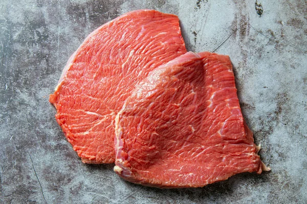 Rått kött. Två skivor färskt rått kött på en svart skifferplatta. Förbereder kött för en grill. Hälsosam, naturlig mat — Stockfoto