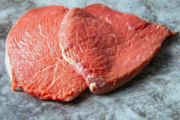 Rått kött. Två skivor färskt rått kött på en svart skifferplatta. Förbereder kött för en grill. Hälsosam, naturlig mat — Stockfoto