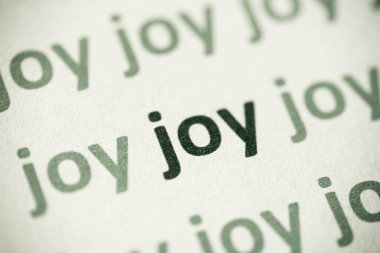 beyaz kağıt makro üzerinde basılı kelime sevinç