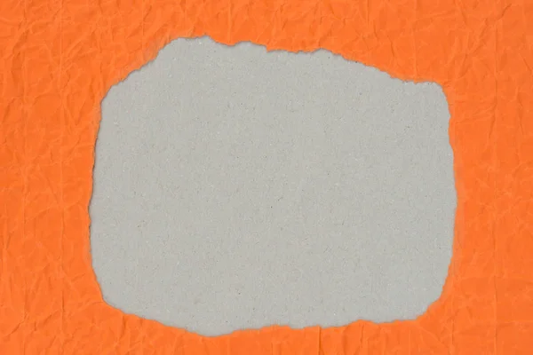Trou de forme irrégulière sur morceau sur papier orange — Photo