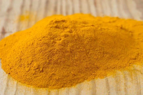 Yığın tumeric baharat ahşap tahta üzerinde — Stok fotoğraf