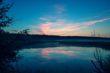 Göl üzerinde büyülü mor gündoğumu. Puslu sabah, kırsal manzara, vahşi hayat