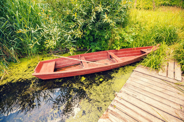 Wooden boat on the river bank at the wooden pier