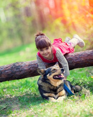 Ormanda köpek oynamaktan mutlu küçük kız. Oturum açma yalan kız