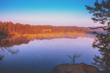 Puslu bir sonbahar sabahı bir dağ Gölü kıyısında kayalık. Norveç'in güzel doğa