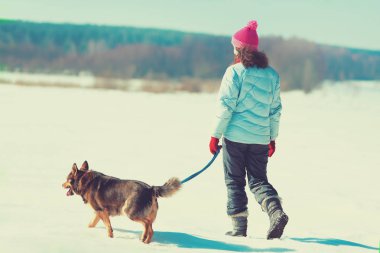 Onu köpek karlı sahada yürüyen genç kadınla. Köpek tasmasını tutan kız