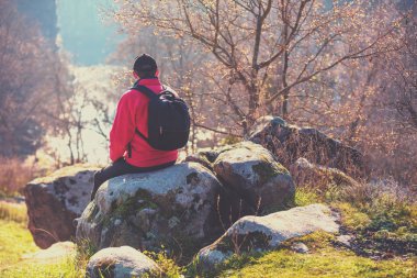Bir turist bir kaya üzerinde bir güzel Kanyon güneşli bir sonbahar gününde oturur. Adam nehre görünüyor