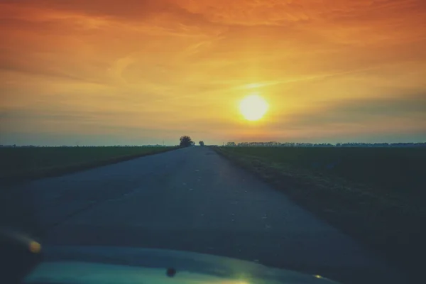 View through the windshield of a country road at sunset. Rural evening landscape