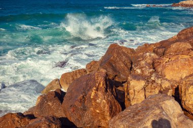 Deniz kayalık sahilde sörf. Sahilde okyanus dalgası. Güneşli bir sahil. Rüzgarlı hava