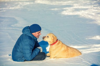Bir adam ve bir köpek en iyi arkadaş. Kışın karlı bir alanda oturan köpekli adam.