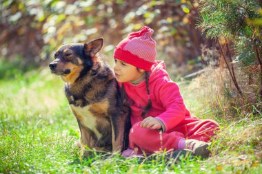 Ormanda köpek oynamaktan mutlu küçük kız