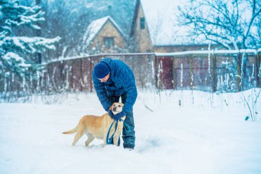 İnsan ve köpek en iyi arkadaşlardır. Yağmurlu bir kışta bir köyde köpekli bir adam yürüyor.