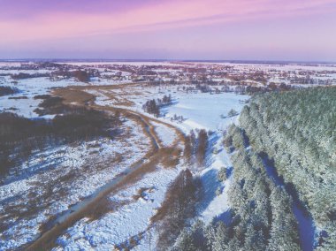 Akşam kış kırsal manzara üst görünümü. Karla kaplı tarlalar, orman ve donmuş dere