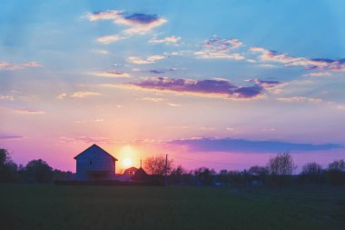 Gün batımında akşam kırsal manzara. Güzel akşam gökyüzüne karşı bir köyün silueti