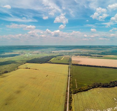 Ekilebilir alanlar ve güzel pitoresk gökyüzü ile yol. Kırsal ve karayolu yukarıdan görünümü. Güneşli bir günde yaz kırsal manzara