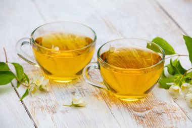 Grunge ahşap masada yasemin çiçekleri ile yeşil çay iki bardak