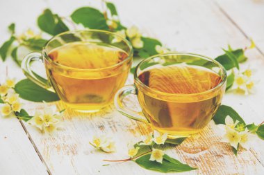 Grunge ahşap masada yasemin çiçekleri ile yeşil çay iki bardak