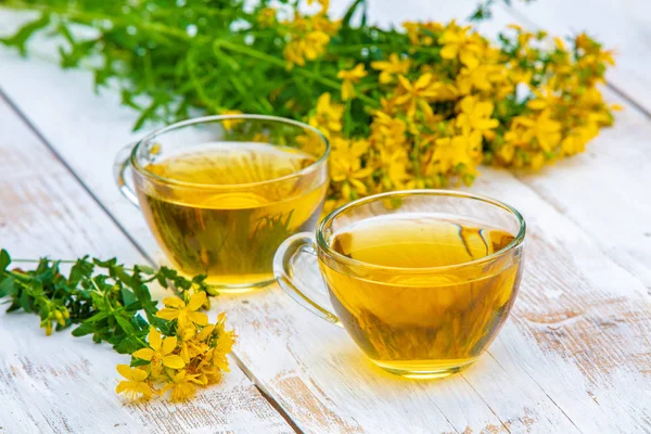 Hypericum bitkisel (Tutsan) çay ahşap grunge masada iki bardak