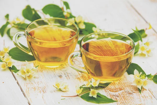 Grunge ahşap masada yasemin çiçekleri ile yeşil çay iki bardak