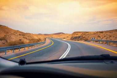 Çölde dağ yolunda araba sürmek. Ön camdan kumtaşı dağların görünümü. Arad'dan Ölü Deniz'e giden yol. İsrail