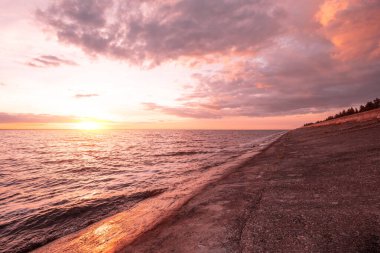 Sabah erkenden. Denizin üzerinde gün doğumu. Deniz kenarındaki beton baraj