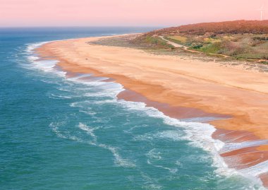 Gün batımında kumlu kayalık deniz kıyısı. Akşamları deniz manzarası. Nazare, Portekiz, Avrupa