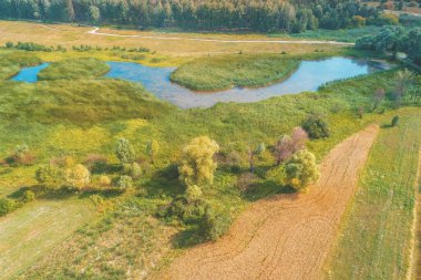 Kırsal alanın havadan görünüşü. Güneşli bir yaz gününde ekilebilir tarla ve dere. Baharda güzel doğa manzarası