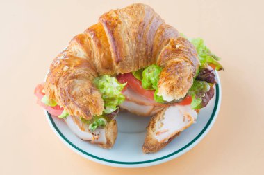 Sandviç kruvasan, marul, domates ve füme hindi.