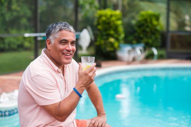 Yakışıklı orta yaş İspanyol adam açık hava yaşam tarzı bir ev ortamında bir yüzme havuzu tarafından.