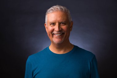 Gri bir geçmişi olan yakışıklı orta yaşlı bir erkek stüdyo resmi..