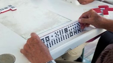 Ağır çekim yüksek tanımlı video yaşlı bir bireysel adamın popüler domino oyunu oynarken.