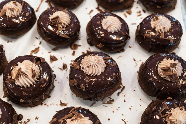 Freshly baked chocolate fudge donuts in a bakery.