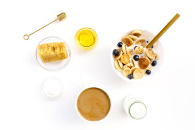 Bal ve bal peteği, yoğurt, süt ve yaban mersinli krep ve beyaz izole edilmiş sütlü kahve.