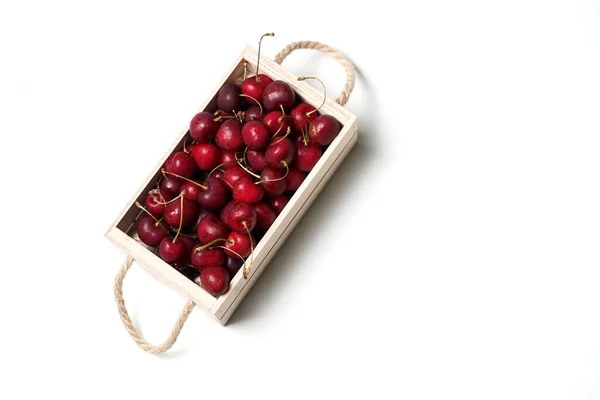 Boîte en bois pleine de cerises douces rouge foncé isolées sur fond blanc — Photo