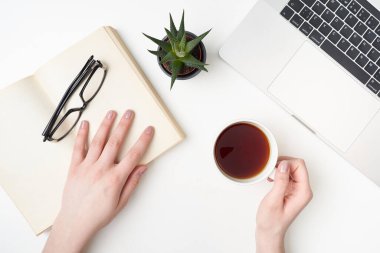 Düz yatıyordu defterle, elinde çay fincanı olan genç bir kadının elleri, sulu, kitap ve bardaklar beyaz üzerine.