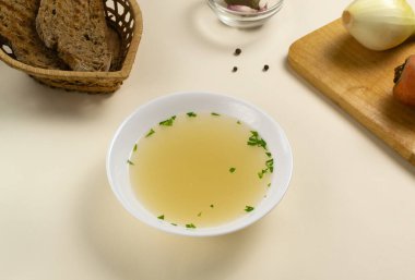 Fresh bouillon in a white plate with herbs and croutons of grain bread. Hot soup made from meat, carrots, onions, garlic and pepper. Horizontal orientation. clipart