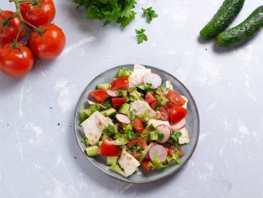 Gri arka planda malzemeleri olan gri tabakta vejetaryen yağlı salata. Üst Manzara. Levantine salatası yağlı, çeşitli sebze ve otlarla birlikte kurutulmuş pide ya da pide ile hazırlanır.. 
