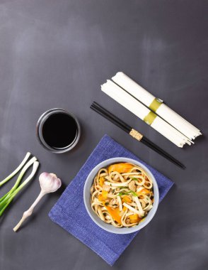 Tavuklu Udon eriştesi, soya sosu, bambu çubukları ve siyah arka planda taze malzemeler. Üst Manzara. Japon mutfağı. Boşluğu kopyala.