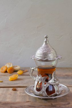 Geleneksel cam bardakta Türk çayı ve ahşap masada kurutulmuş meyveler. Dikey oryantasyon. Boşluğu kopyala.
