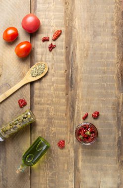 Cam kavanozda güneşte kurutulmuş domatesler ve ahşap arka planda baharatlar. Üst Manzara. Boşluğu kopyala.