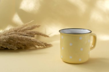 Sarı arka planda tarla bitkileriyle seramik sarı bir fincanda bir fincan siyah çay. Seçici odaklanma. Yatay yönelim.