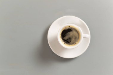 Beyaz fincanda espresso, köpüklü kahve ve gri arka planda beyaz bir fincan. Seçici odaklanma. Uzayı kopyala Üst görünüm.