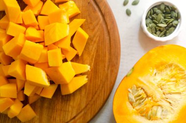 Tahta bir tahtanın üzerinde tohumlarla dilimlenmiş balkabağı. Yemek pişirme süreci. Sonbahar yemeği. Seçici odaklanma. Yatay oryantasyon. Üst görünüm