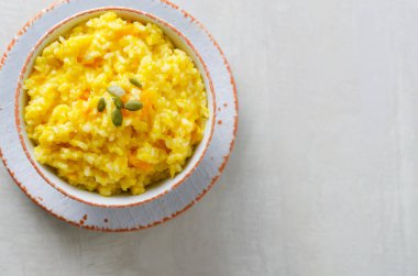 Gri bir masada beyaz ve turuncu bir kasede balkabaklı risotto. İtalyan yemeği konsepti. Sonbahar yemeği. Seçici odaklanma. Yatay oryantasyon. Üst Manzara. Boşluğu kopyala