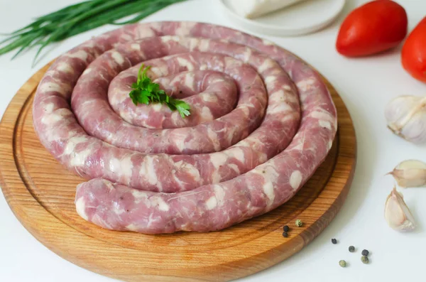 Çiğ ev yapımı sosis et ve pastırma parçaları beyaz bir masada tahta kesme tahtasında sarımsak ve biberle. Geleneksel gıda konsepti. Yatay oryantasyon. Seçici odaklanma. Üst görünüm