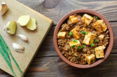 Baharatlı soslu Mapo tofu tabağı ve ahşap bir arka planda seramik kasede kıyma. Sichuan bölgesinden bir tabak. Geleneksel Asya yemekleri konsepti. Seçici odaklanma. Yatay oryantasyon. Üst görünüm.
