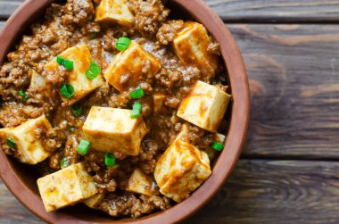Baharatlı soslu Mapo tofu tabağı ve ahşap bir arka planda seramik kasede kıyma. Sichuan bölgesinden bir tabak. Geleneksel Asya yemekleri. Seçici odaklanma. Yatay oryantasyon. Üst görünüm.
