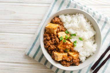 Baharatlı soslu Mapo tofu yemeği ve beyaz arka planda kıymalı biftek kasesi. Sichuan bölgesinden bir tabak. Geleneksel Asya yemekleri konsepti. Seçici odaklanma. Yatay oryantasyon. Üst görünüm.