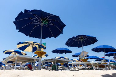 Sahilde mavi yaz gökyüzüne karşı şemsiyeler açık..